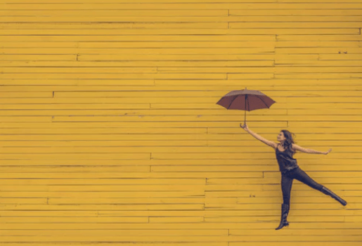 En av många gratis bilder på nätet - i detta fallet en kvinna som håller ett paraply mot en gul bakgrund.